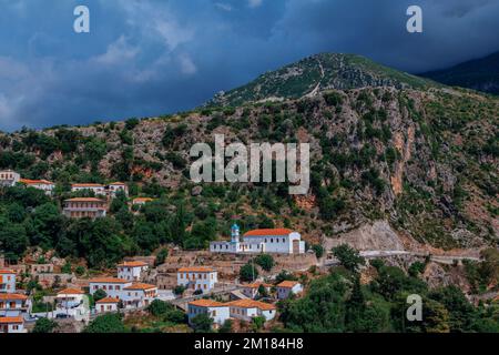 Vuno, Albania - August 7, 2020: view of the village - traditional white houses with orange roofs and wooden shutters on windows - on the mountain hill Stock Photo