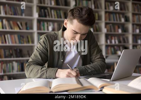 Positive busy hardworking student guy writing draft, notes Stock Photo
