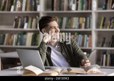 Happy dreamy student guy working on scientific article Stock Photo