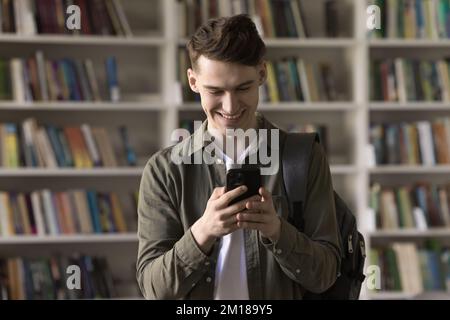 Happy student guy using learning application for study on smartphone Stock Photo