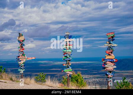 Pyatigorsk, Russia. 2022, October 24. Direction to different places of the world indicated in a street signs. Landscape on the mountain post with pointers cities and wooden bench on the peak Stock Photo