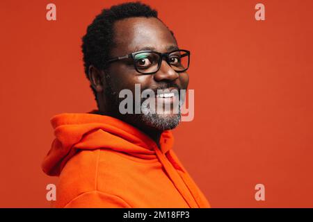 Adult african american man wearing eyeglasses smiling at camera isolated over orange background Stock Photo