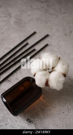 Transparent bottle of aroma diffuser. Parfum for home with cotton flowers. Trending concept, natural materials. Vertical photo on a marble background Stock Photo