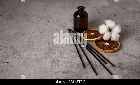 Transparent bottle of aroma diffuser. Parfum for home with cotton flowers and orange fruit. Trending concept, natural materials on a marble background Stock Photo