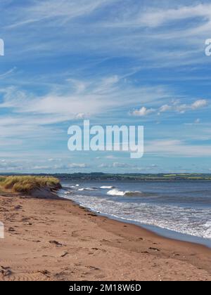 Waves coming in against the grass covered dunes of Tentsmuir point at the far point of the Estuary mouth. Stock Photo