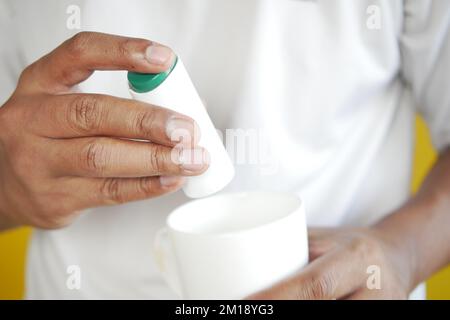 young man putting artificial sweetener in tea, Stock Photo