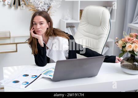 Business woman sitting at her desk distracted from her work and looking at the camera. Stock Photo