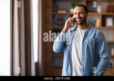 Portrait Of Smiling Handsome Black Man Talking On Cellphone At Home Stock Photo