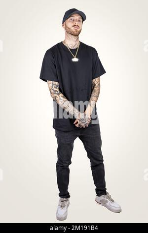 tattooed rap singer posing in studio wearing black clothes on a white ...