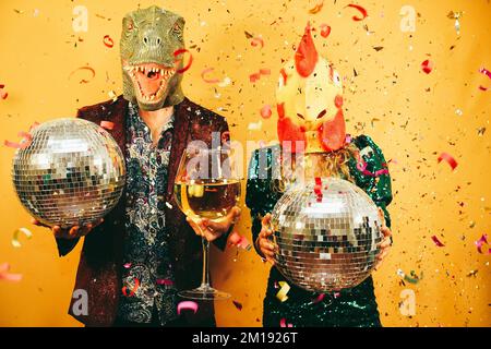 Crazy couple having fun holding disco balls and champagne glass at party - Main focus on hand holding glass Stock Photo