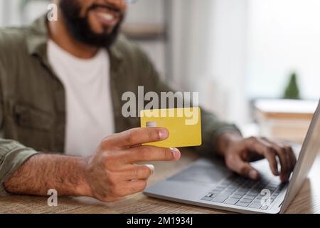 Online payment concept. Closeup shot of man with laptop and credit card in hands shopping online, cropped Stock Photo