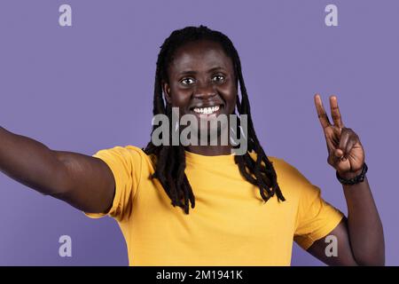 Closeup of cheerful young black man taking selfie on purple Stock Photo
