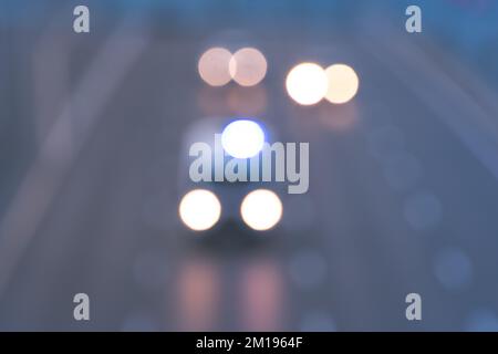 Defocused traffic with an ambulance car on the highway with headlights on. Stock Photo
