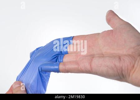 The doctor takes off his blue rubber gloves, the skin on his hands is wrinkled from moisture. Wrinkled fingers after wearing rubber gloves for a long Stock Photo