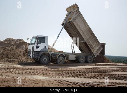 gray dump truck at the construction site in the process of transporting soil unloading. Excavation. Commercial vehicle for construction business Stock Photo