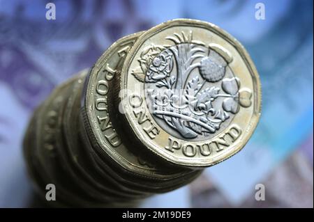 A STACK OF BRITISH ONE POUND COINS ON BRITISH NOTES RE THE ECONOMY RECESSION INFLATION MONEY SPENDING ETC UK Stock Photo