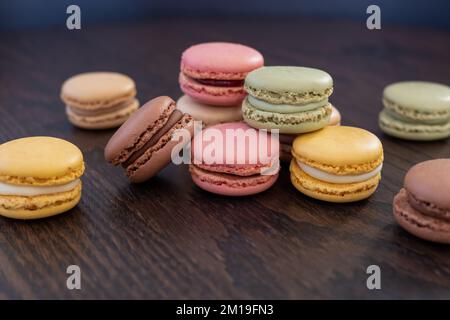 randomly arranged fresh and colorful macarons on dark wooden table Stock Photo