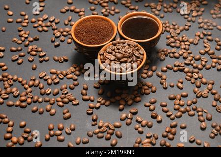 Set of three cups of coffee beans, ground and drink on black background, top view of coffee. Stock Photo