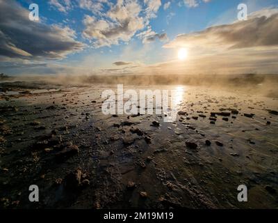 Serene sunset over geothermal landscape Hverir with steam and rocky terrain near Myvath in Iceland Stock Photo