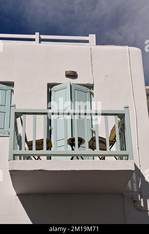 Mykonos, Greece - June 2022: Table and chairs on a small balacony on the upper floor of a house in the centre of the town. No people. Stock Photo