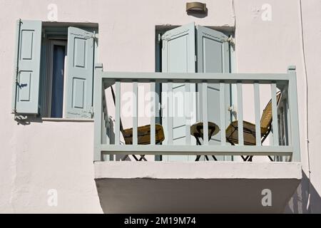 Mykonos, Greece - June 2022: Table and chairs on a small balacony on the upper floor of a house in the centre of the town. No people. Stock Photo