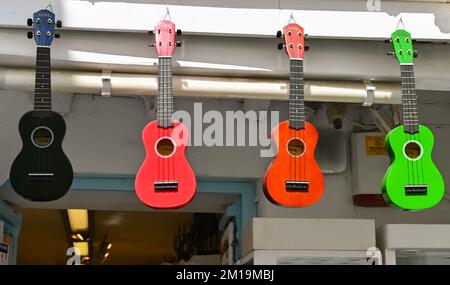 Mykonos, Greece - June 2022: Row of small guitars in different colours hanging outside a shop in the centre of the town. No people. Stock Photo