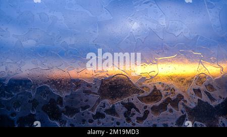 wintry frosty pattern on glass. abstract background of ice frozen window. winter day, sun shine through frosted glass on window Stock Photo