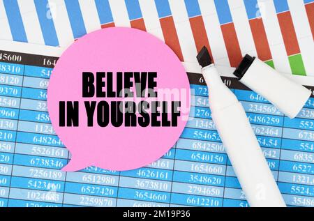 Business and economics concept. On financial statements and charts there is a marker and a sticker with the inscription - BELIEVE IN YOURSELF Stock Photo