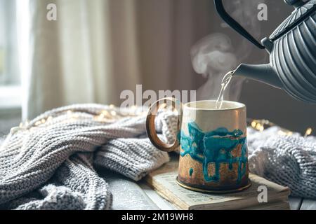 Beautiful handmade ceramic cup on a blurred background with a knitted element. Stock Photo
