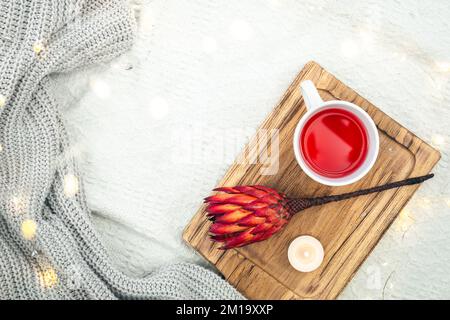 A cup of red tea and a flower on a wooden tray in bed, top view. Stock Photo