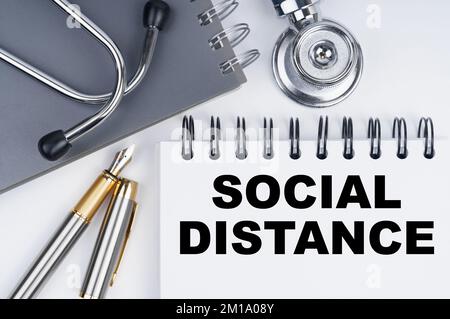 Medicine and health concept. On the table are a stethoscope, a pen and a notebook with the inscription - SOCIAL DISTANCE Stock Photo