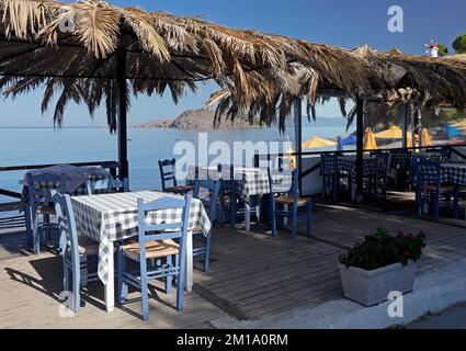 Blue and white check tablecloths and blue hairs at empty seaside  taverna early morning, Lesbos, Greece Taken September / October 2022. Stock Photo