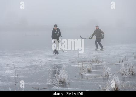Bluntisham, Cambridgeshire, UK. 11th Dec, 2022. People make the most of the freezing weather skating on the frozen fen washes in freezing fog. After several days of sub zero temperatures the winter weather has allowed the shallow fenland water to freeze over to allow outdoor fen skating. The cold snap is forecast to last into the coming week. Credit: Julian Eales/Alamy Live News Stock Photo