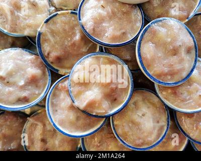 Khanom or Kanom Kluay is a Thai banana cake dessert made of steamed banana, rice flour and coconut milk. Served on ceramic cup. Street food, Bangkok, Stock Photo