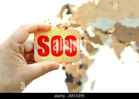 Medicine and health concept. Against the background of the world map, a man holds a sign with the inscription - SOS Stock Photo