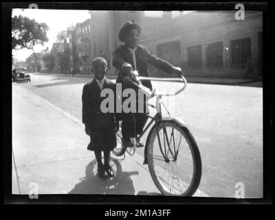 Two boys, one riding a bicycle , Boys, Bicycles & tricycles. Jack Miller Collection Stock Photo