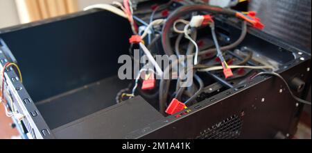 Desktop computer, black empty case and various cables, which are tried to be assembled in a home environment Stock Photo