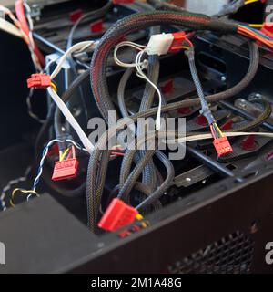 Desktop computer, black empty case and various cables, which are tried to be assembled in a home environment Stock Photo