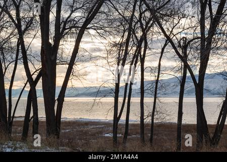 Sun Setting Behind the Distant Hills Seen through The Silhouetted Trees Stock Photo