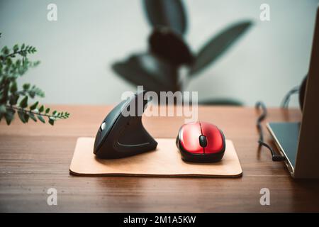 Ergonomic mouse and normal computer mouse. Black vertical optical computer mouse with ergonomic design, designed to reduce injuries such as carpal tun Stock Photo