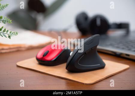 Ergonomic mouse and normal computer mouse. Black vertical optical computer mouse with ergonomic design, designed to reduce injuries such as carpal tun Stock Photo