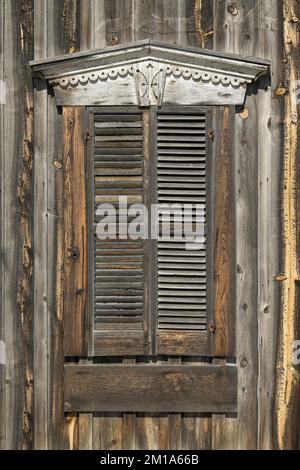 Weathered old wooden shutters on exterior wooden wall Stock Photo