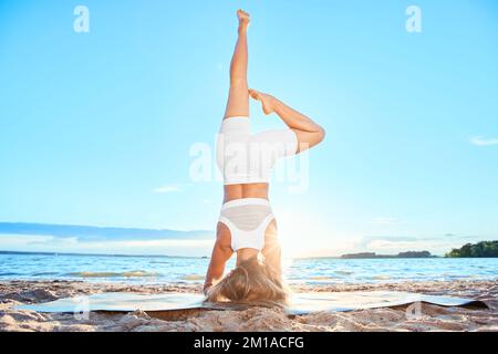 athletic young woman practicing yoga on the riverbank. Standing Stock Photo
