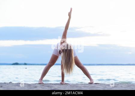 young woman doing physical education on the shore of the lake. Stock Photo