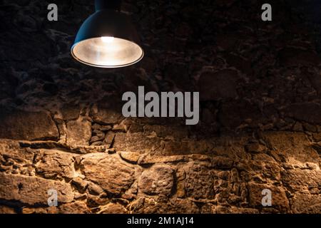 Metal lamp lighting the old stone wall in the darkness Stock Photo