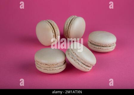 Closeup of beige macaron cakes on red background Stock Photo