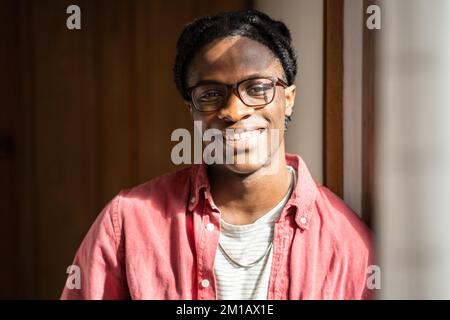 Happy optimistic young African American guy standing at home expressing positive emotions Stock Photo