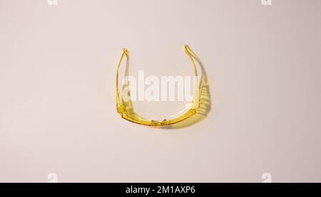 Yellow plastic protective goggles for workers on a beige background, top view Stock Photo