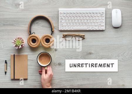 Unretirement concept image. Flat lay with modern office supplies - notebook, computer keyboard, mouse, succulent plant. Paper with text, caption Unret Stock Photo