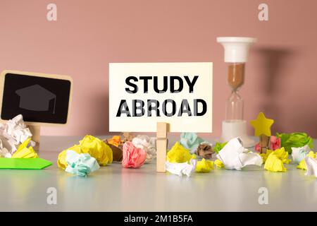 The text Study Abroad appearing behind torn brown paper. Stock Photo